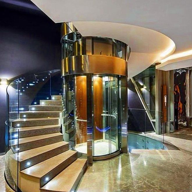 Spiral staircase with a glass elevator in the middle of it 
